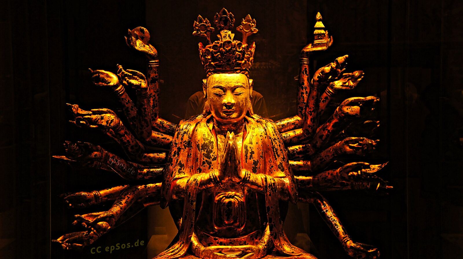 A gilded statue of a multi-armed bodhisattva sits in meditative pose, representing mindfulness and inner peace.