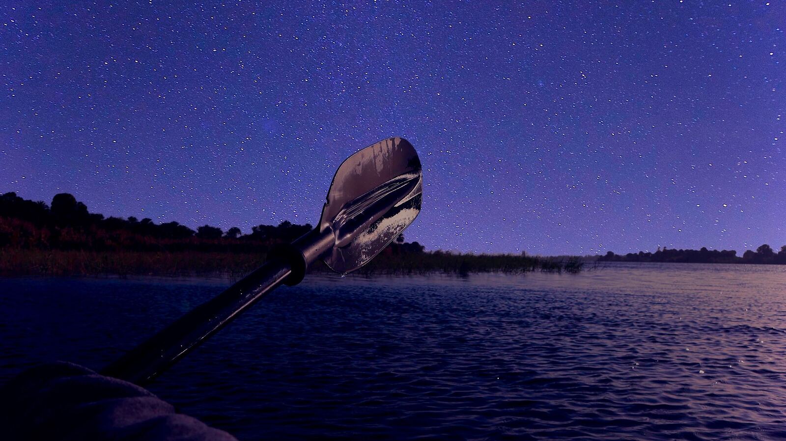 Kayak Paddle | Body Feels A kayak paddle rests on dark water beneath a starry night sky, evoking peaceful mindfulness.